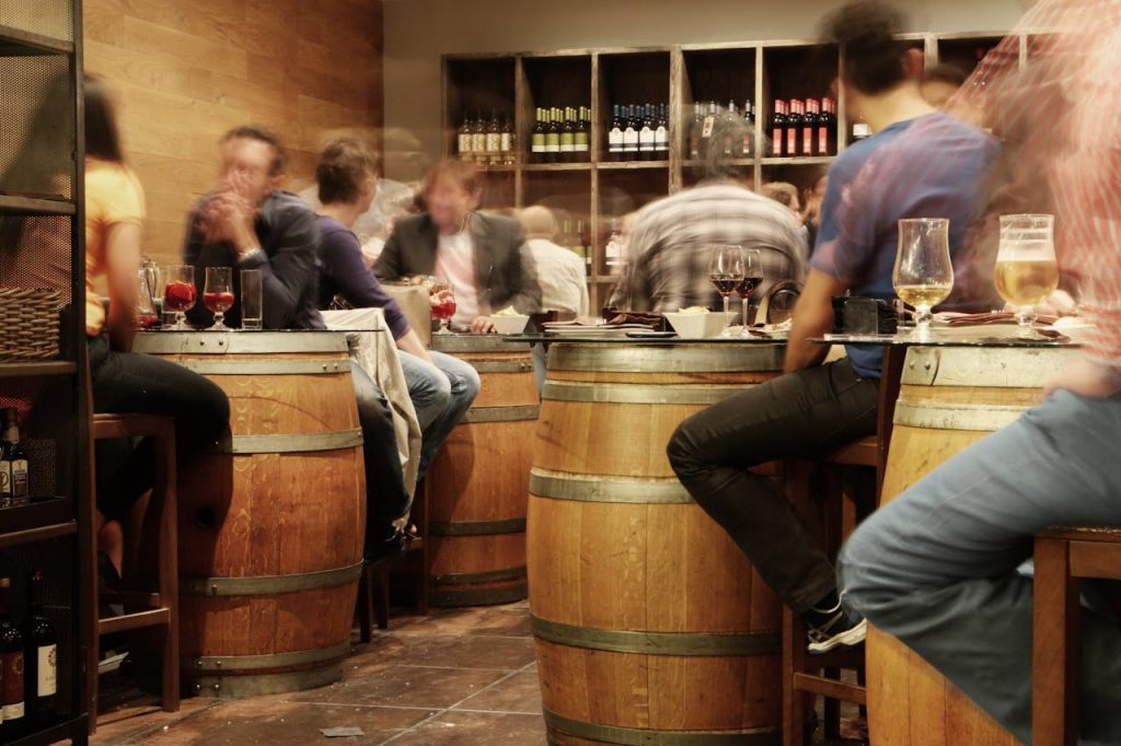 restaurant-alcohol-bar-drinks Lively bar setting with people enjoying drinks and tapas around wine barrel tables.